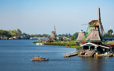 Zaanse Schans windmills and boat on the river near Amsterdam.