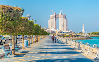 Abu Dhabi Corniche with skyscrapers and waterfront promenade, part of full-day sightseeing tour.