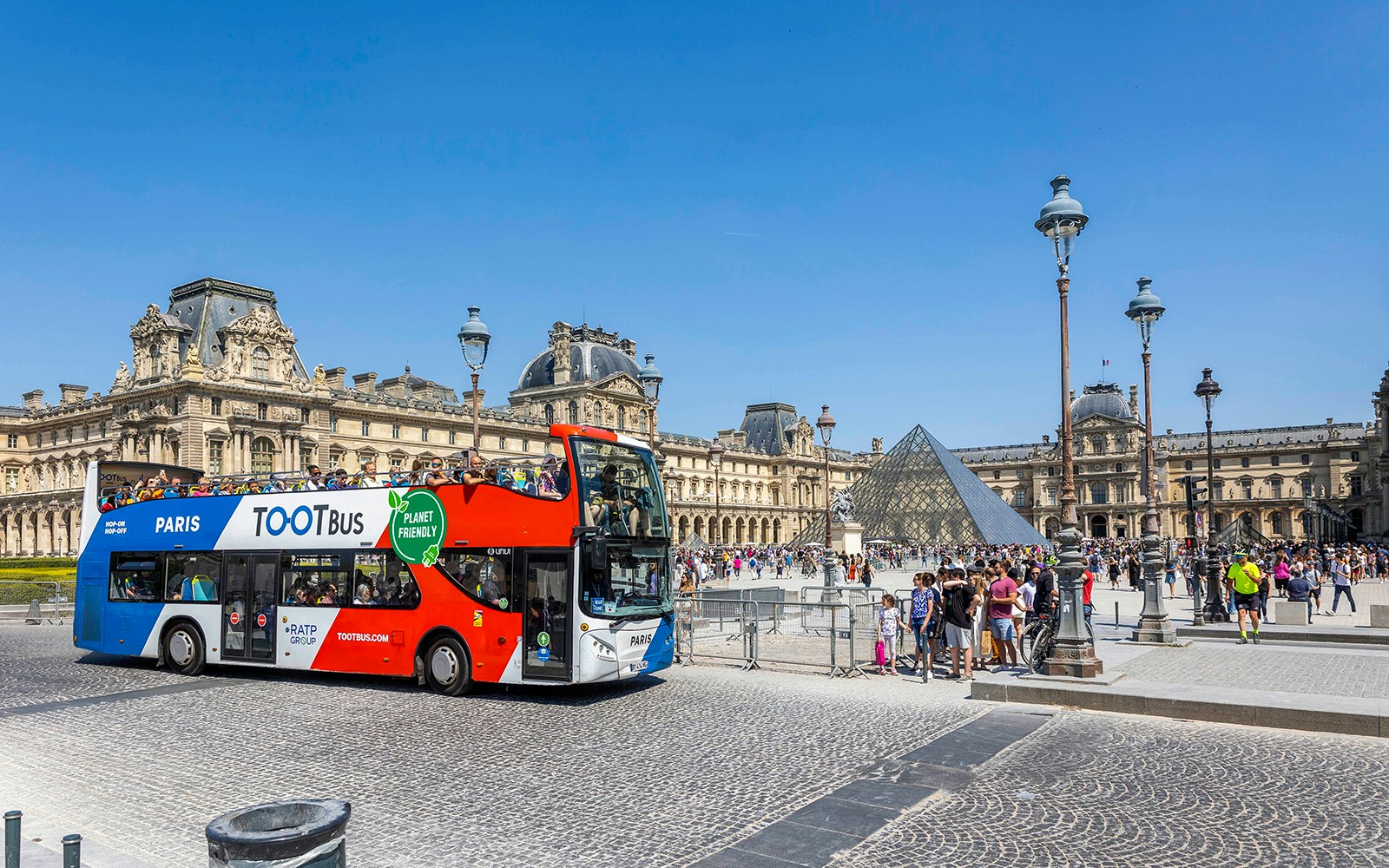 Tootbus double-decker bus in front of the Louvre Museum, Paris.
