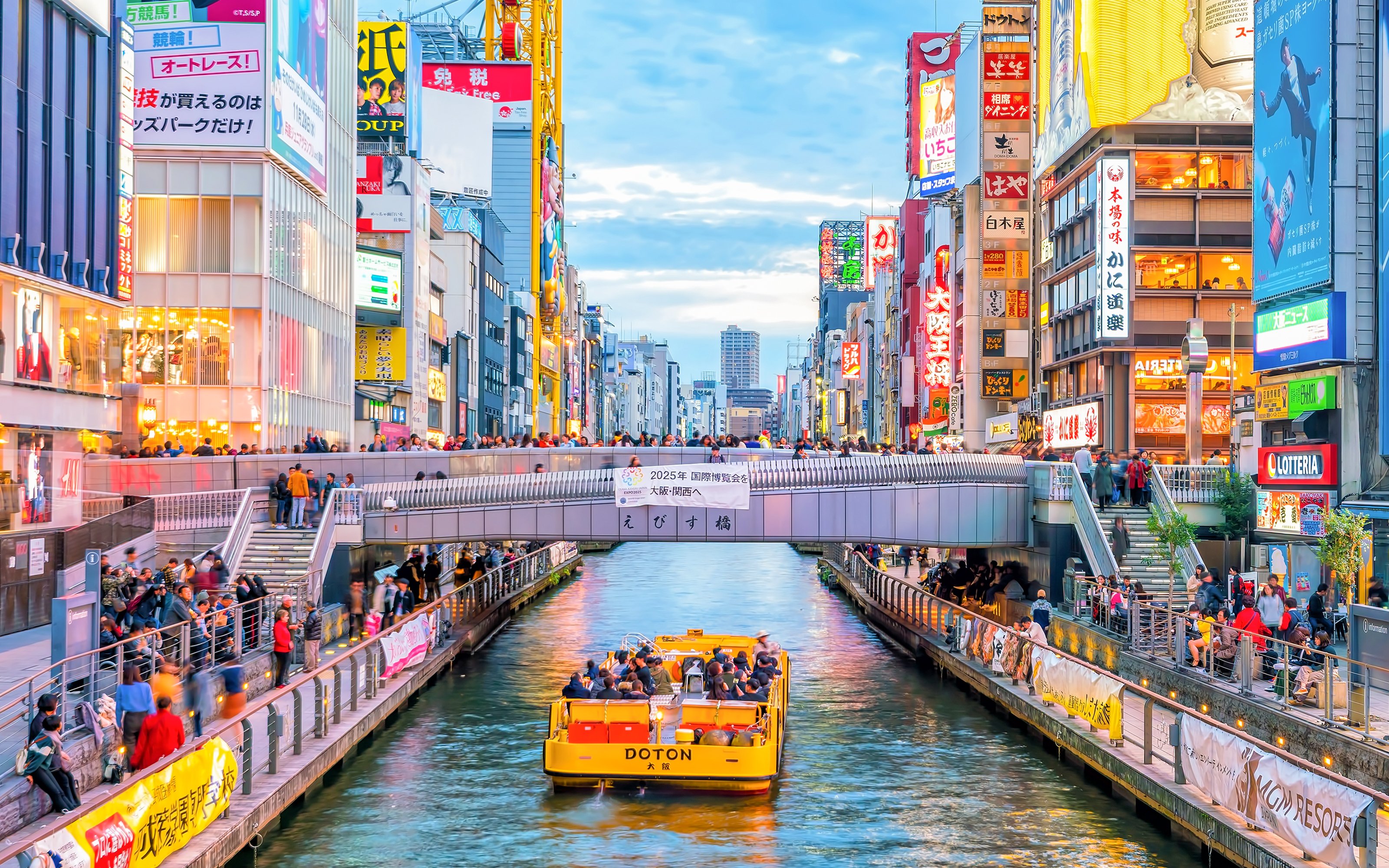 Boat tour on Dotonbori Canal with vibrant cityscape in Osaka, Japan.
