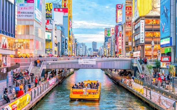 Boat tour on Dotonbori Canal with vibrant cityscape in Osaka, Japan.