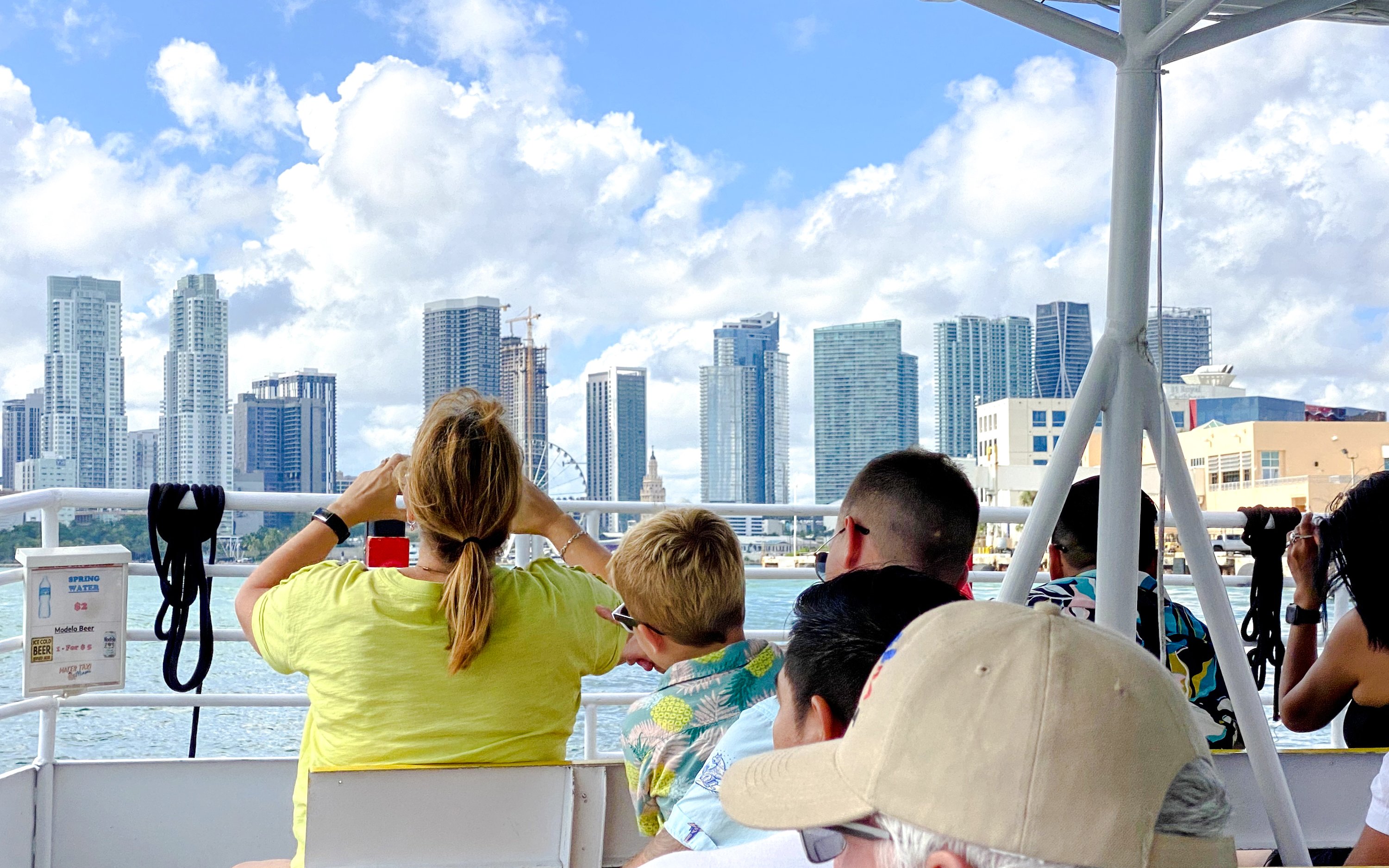 Tourists enjoying a luxury yacht cruise with a view of Miami skyline.