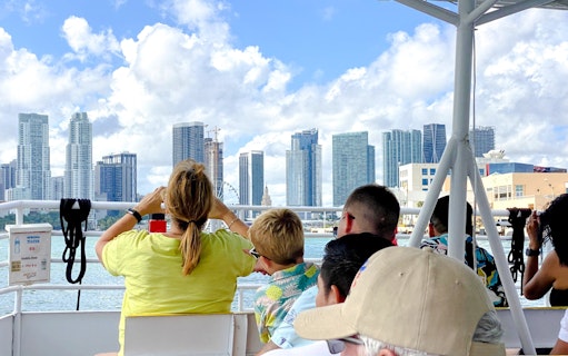 Tourists enjoying a luxury yacht cruise with a view of Miami skyline.