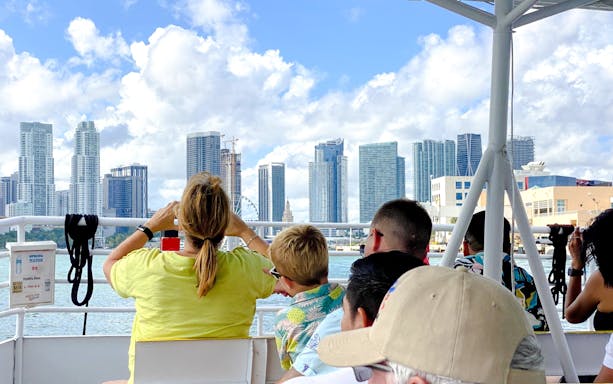 Tourists enjoying a luxury yacht cruise with a view of Miami skyline.