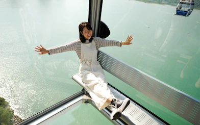 Person enjoying Ngong Ping Cable Car ride with scenic ocean view.