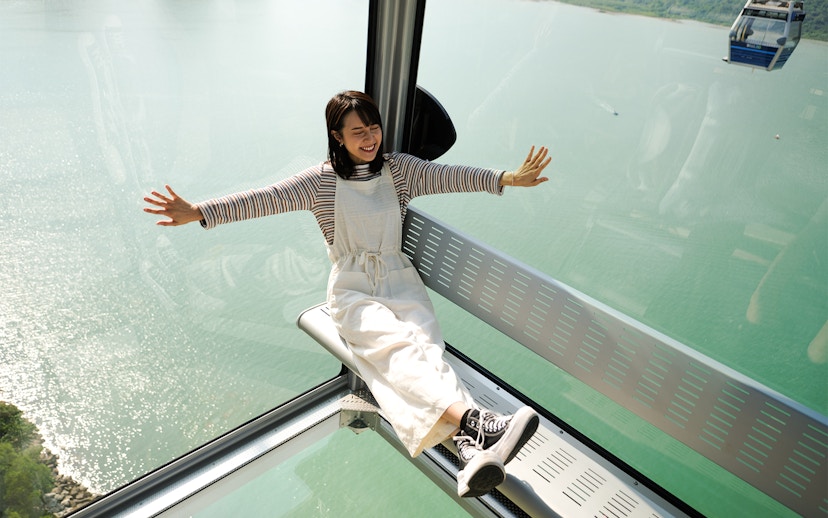 Person enjoying Ngong Ping Cable Car ride with scenic ocean view.