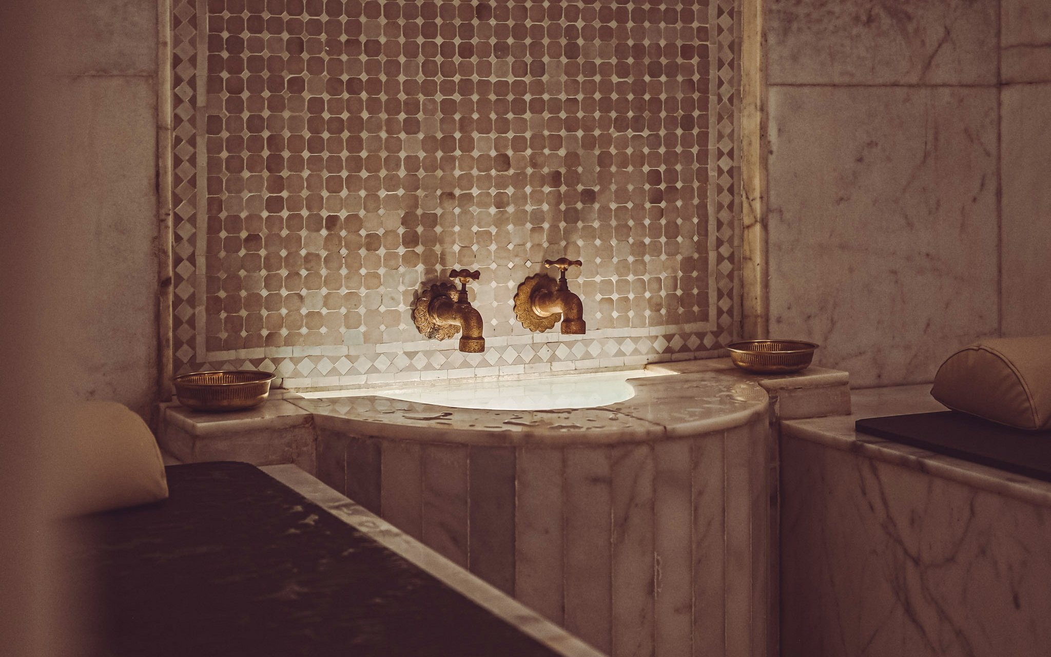 Luxury steam hammam with marble basin and ornate taps.