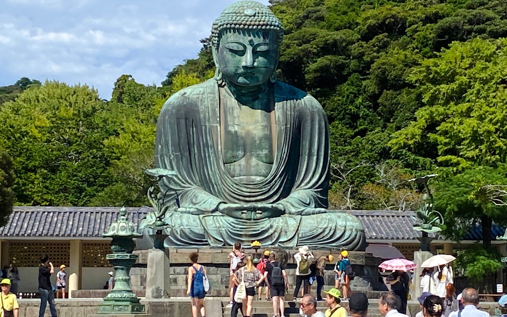 Giant Buddha statue surrounded by tourists on Big Buddha Day Tour in Kamakura, Japan.