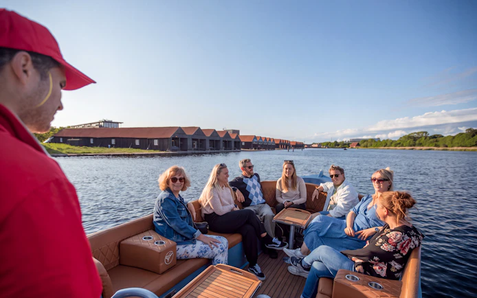 Group enjoying a canal tour in Copenhagen from Ved Stranden, passing historic waterfront buildings.