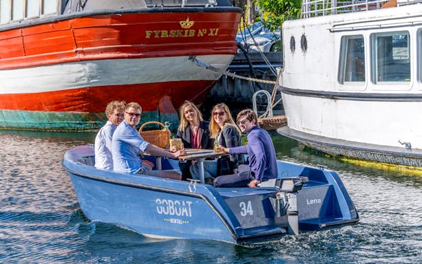 Guests enjoying a boat tour in Copenhagen harbor, passing by historic ships.