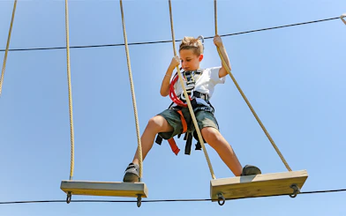 Child on rope course at Oltremare park, Italy, engaging in an interactive activity.