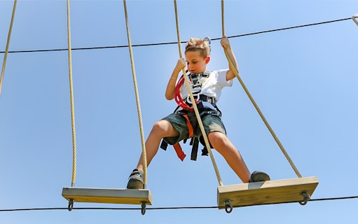 Child on rope course at Oltremare park, Italy, engaging in an interactive activity.