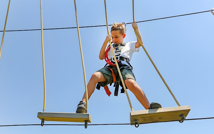 Child on rope course at Oltremare park, Italy, engaging in an interactive activity.