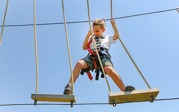 Child on rope course at Oltremare park, Italy, engaging in an interactive activity.