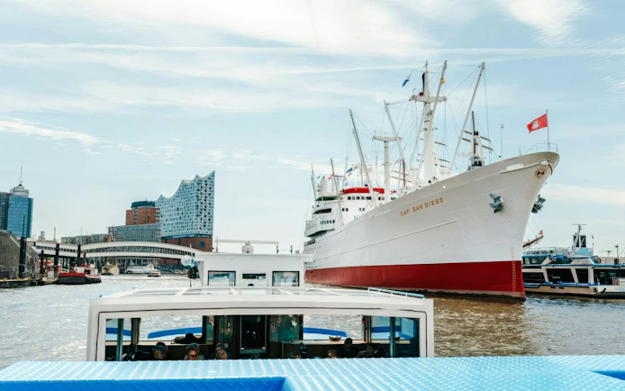 Harbor cruise boat passing Cap San Diego ship in Hamburg's Speicherstadt canal.