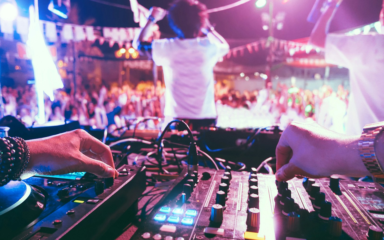 DJ mixing music at a lively outdoor party in Ibiza, Spain.