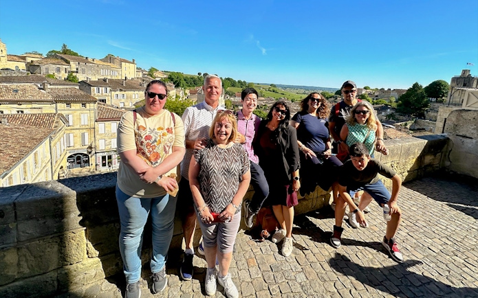 Tour group enjoying a sunny day in Saint-Emilion village with historic buildings in the background.
