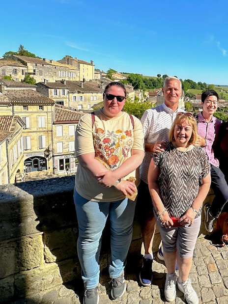 Tour group enjoying a sunny day in Saint-Emilion village with historic buildings in the background.