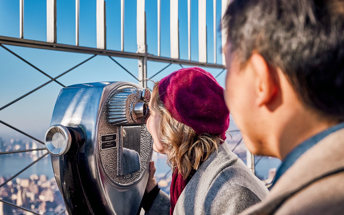 Visitors using a telescope on the 86th Floor Observation Deck, New York City.