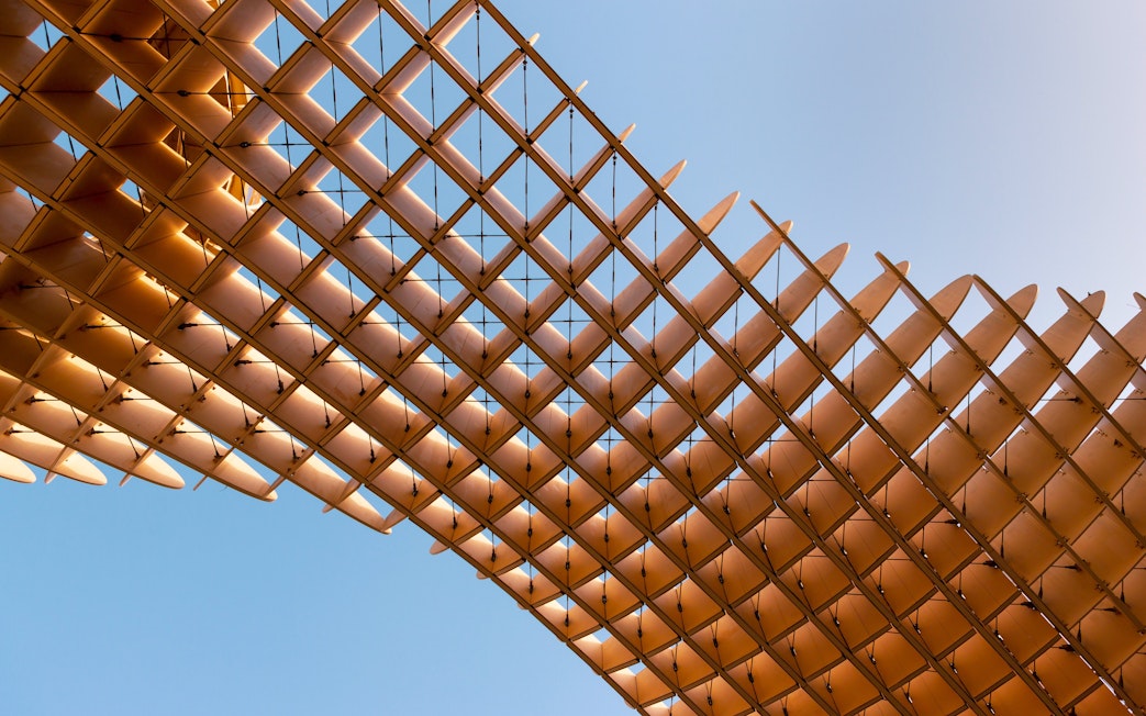 Roof structure of Las Setas in Seville with wooden lattice design against blue sky.