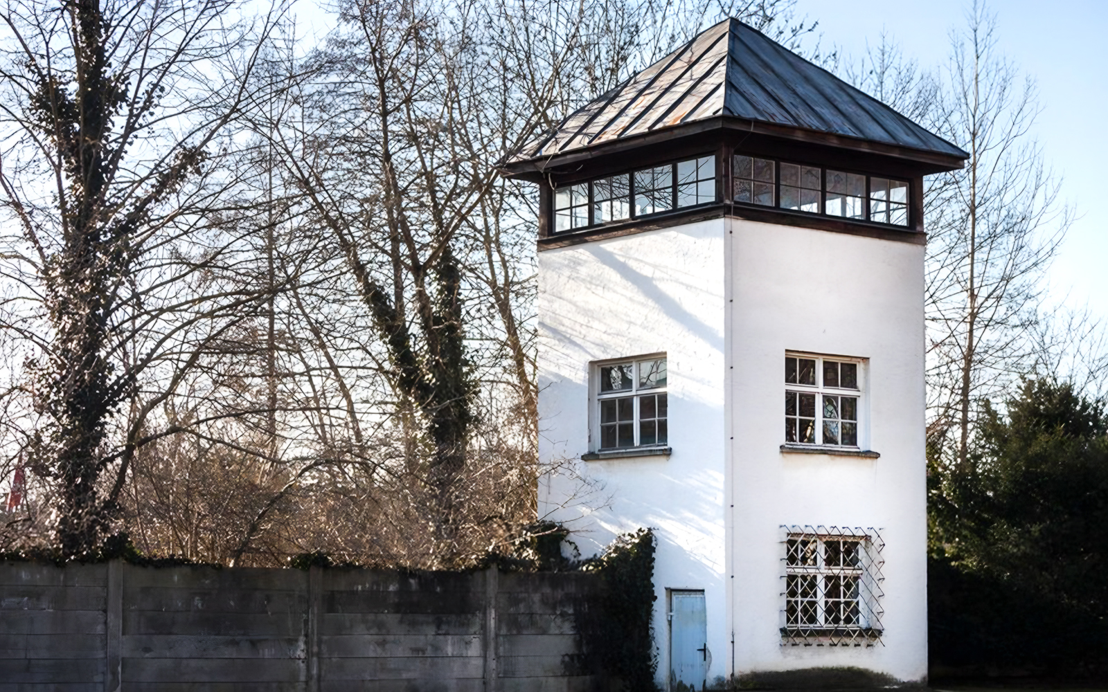 Dachau Concentration Camp watchtower surrounded by trees, part of a guided tour from Munich.