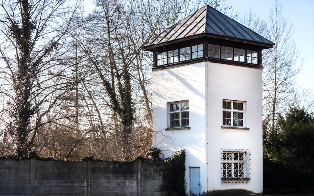 Dachau Concentration Camp watchtower surrounded by trees, part of a guided tour from Munich.