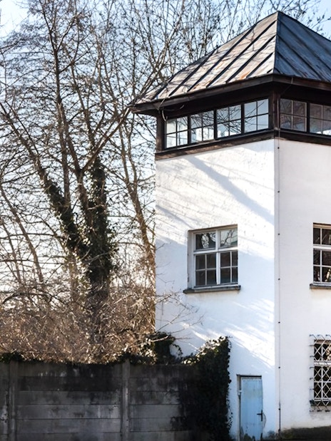 Dachau Concentration Camp watchtower surrounded by trees, part of a guided tour from Munich.