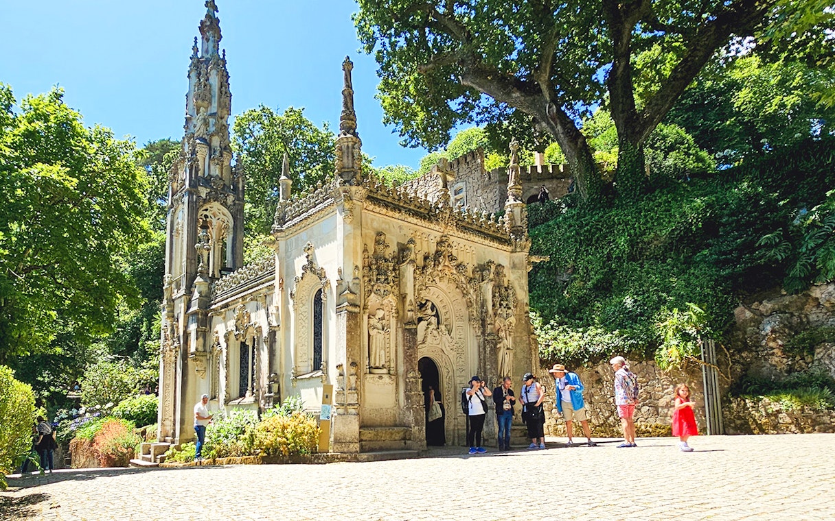 Quinta da Regaleira chapel with tourists exploring the ornate architecture in Sintra, Portugal.