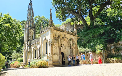 Quinta da Regaleira chapel with tourists exploring the ornate architecture in Sintra, Portugal.
