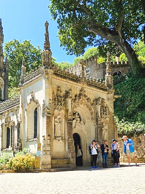 Quinta da Regaleira chapel with tourists exploring the ornate architecture in Sintra, Portugal.