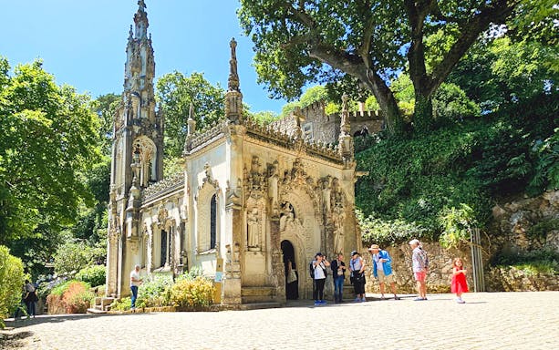 Quinta da Regaleira chapel with tourists exploring the ornate architecture in Sintra, Portugal.