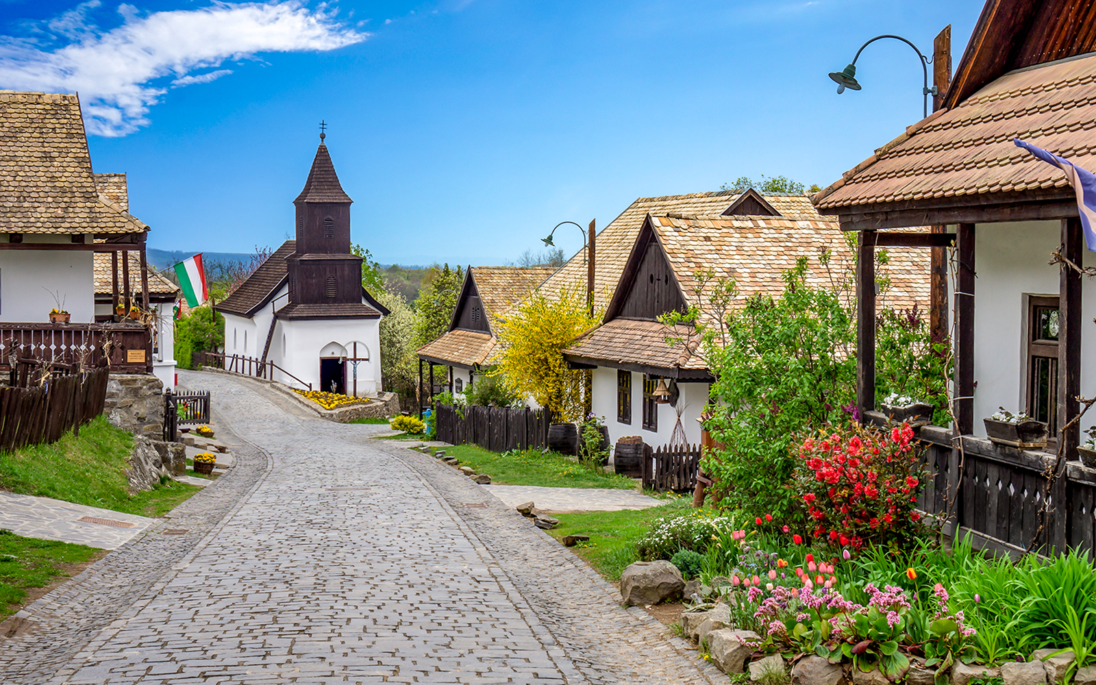 Holloko village street with traditional wooden houses and church, Hungary.