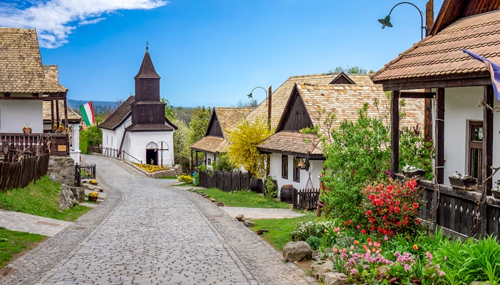 Holloko village street with traditional wooden houses and church, Hungary.