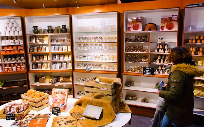 Choco-Story Paris shop with shelves of chocolate products and a visitor browsing.