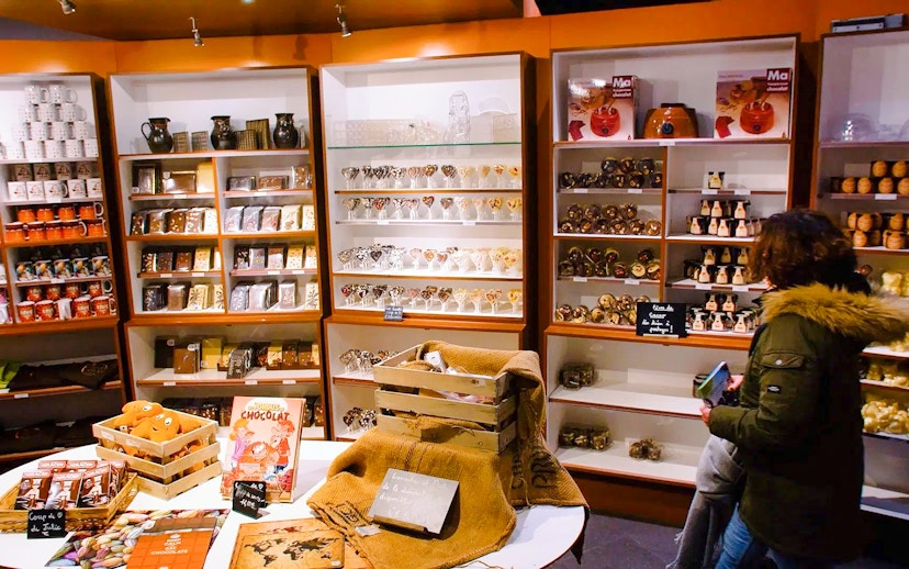 Choco-Story Paris shop with shelves of chocolate products and a visitor browsing.