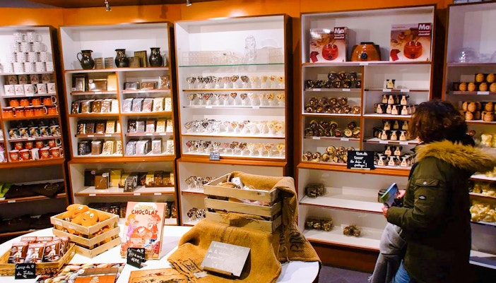 Choco-Story Paris shop with shelves of chocolate products and a visitor browsing.
