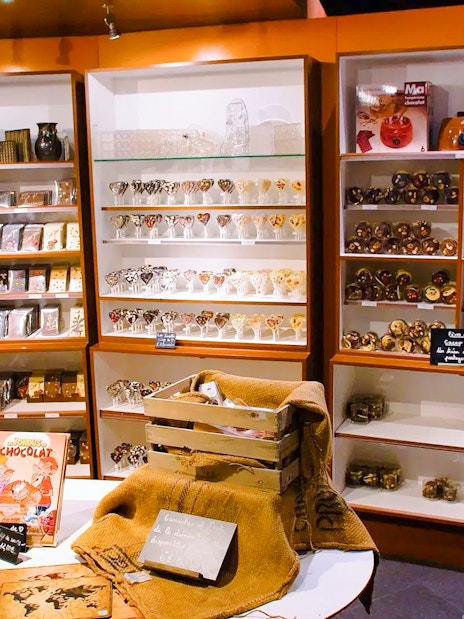 Choco-Story Paris shop with shelves of chocolate products and a visitor browsing.