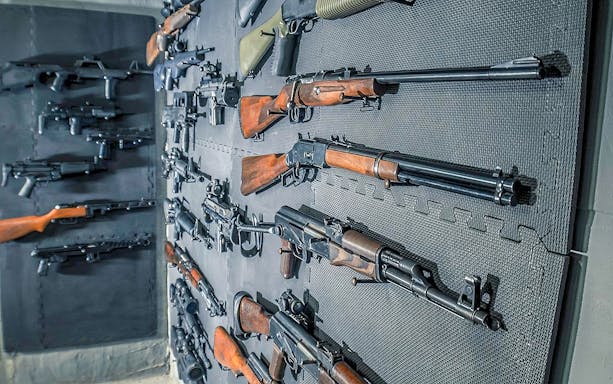 Rifles and firearms displayed on a wall at a shooting range in Warsaw.