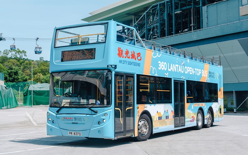 Open-top bus for Lantau Island Hop-on Hop-off Tour near cable cars.