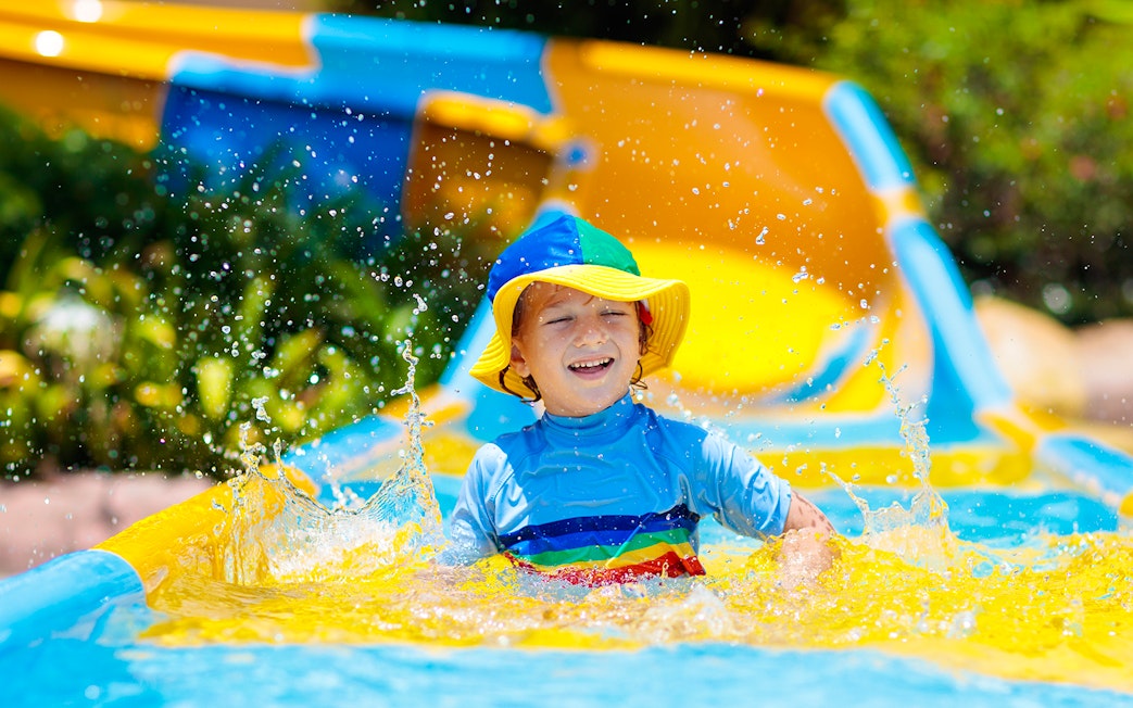 Child enjoying a colorful water slide at a water park.