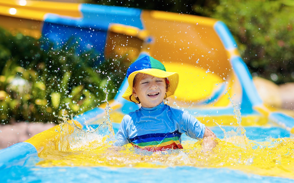 Child enjoying a colorful water slide at a water park.