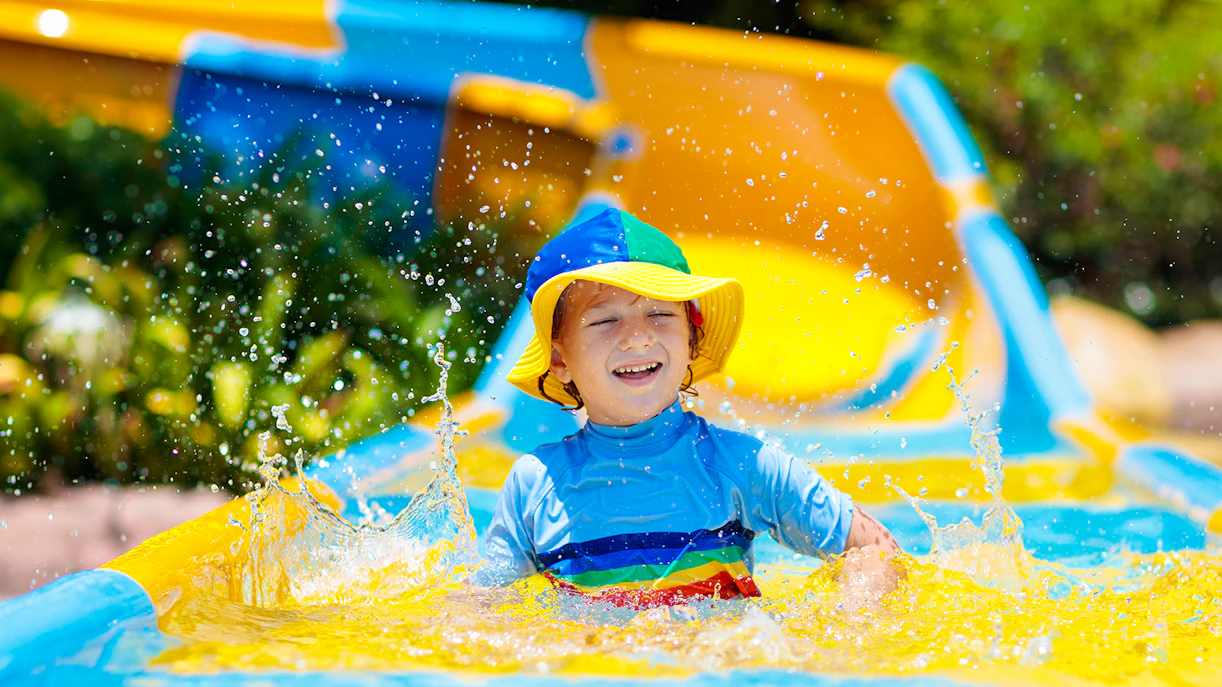 Child enjoying a colorful water slide at a water park.