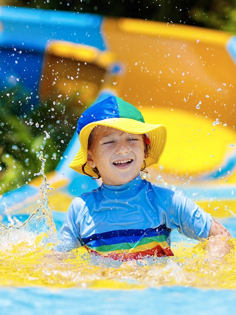 Child enjoying a colorful water slide at a water park.