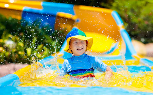 Child enjoying a colorful water slide at a water park.