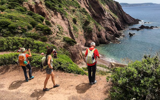 Hikers on the Faraglioni path from Nebida overlooking the coastline.