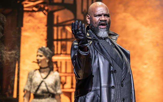 Stage performance of Hadestown in West End with actor in dramatic pose.