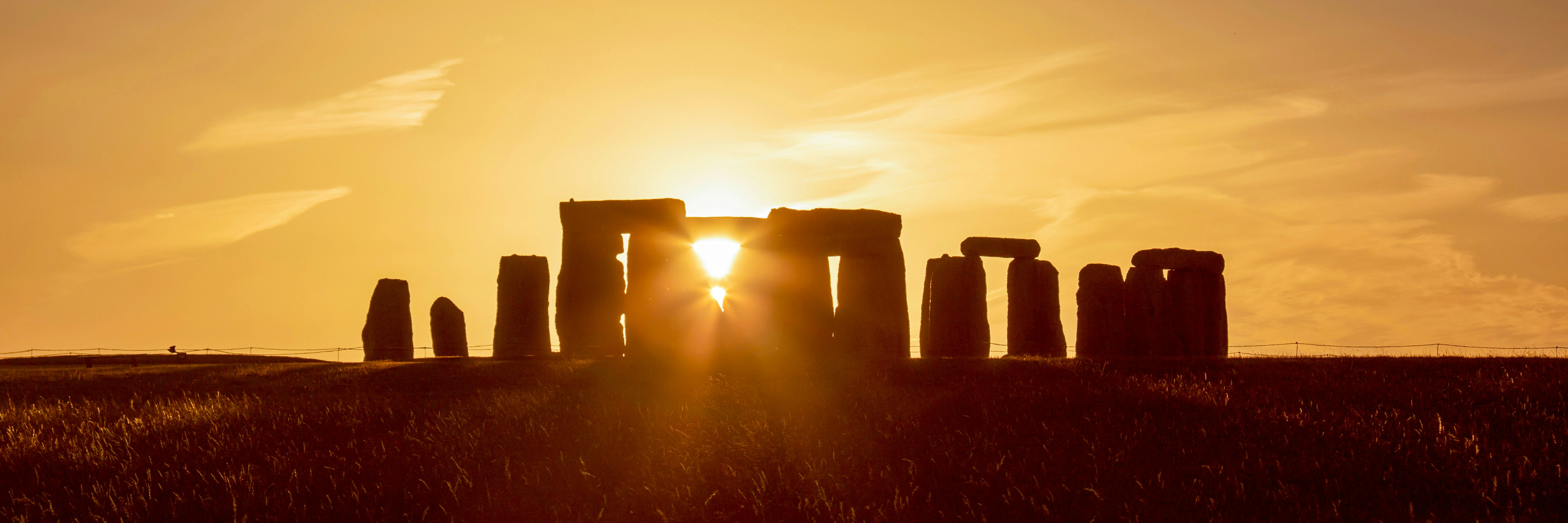 Stonehenge during summer solstice with sun setting behind the stones.