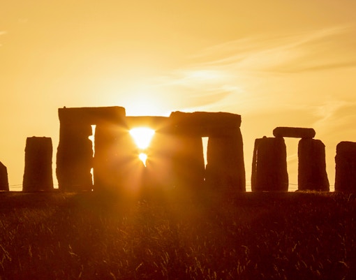 Stonehenge during summer solstice with sun setting behind the stones.