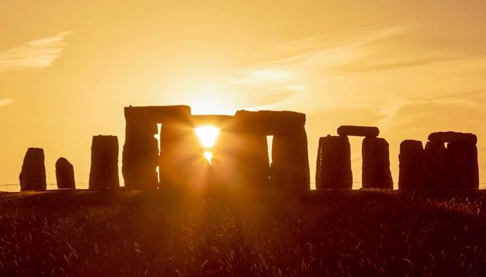 Stonehenge during summer solstice with sun setting behind the stones.