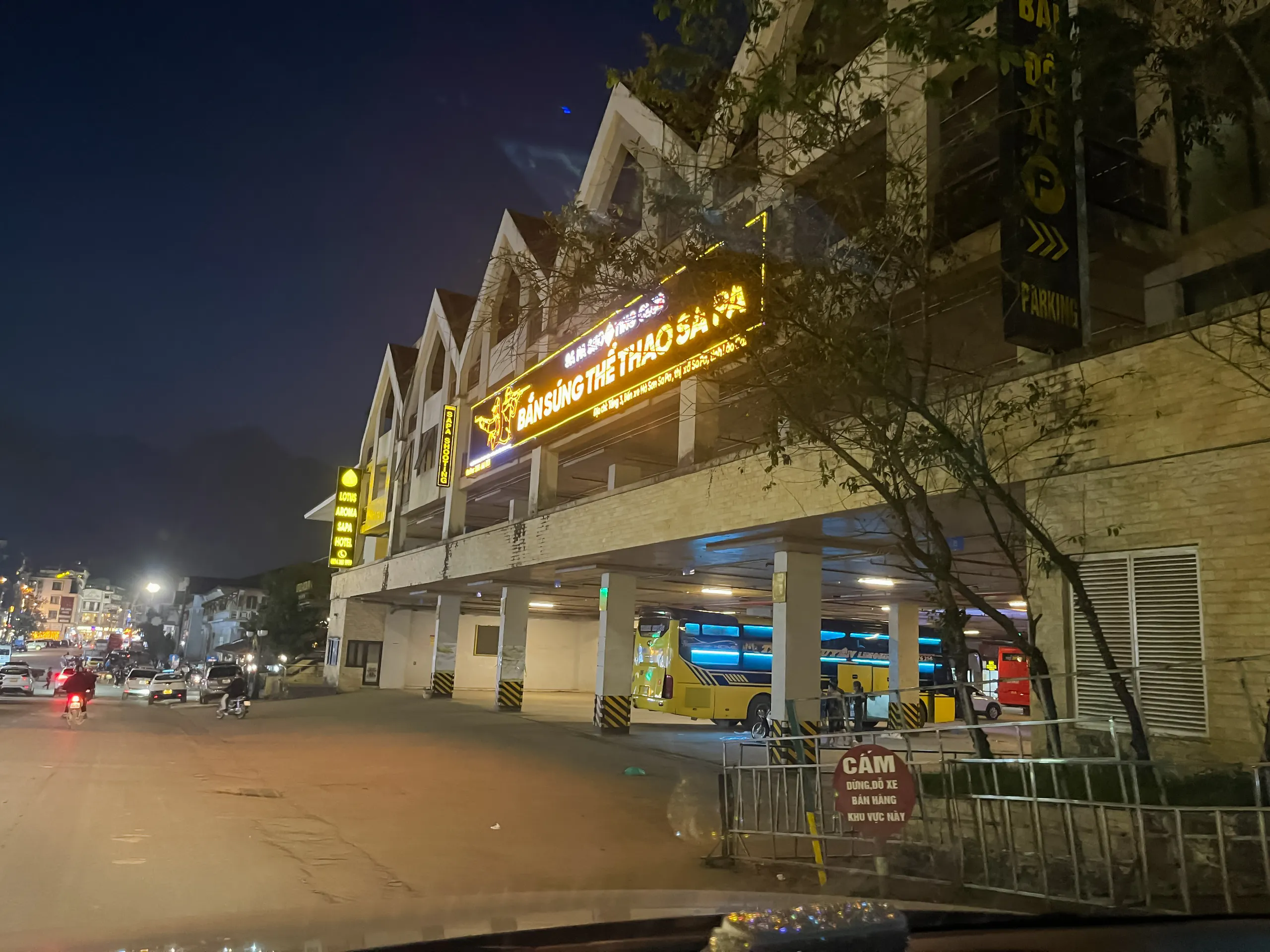 Sapa night street view with illuminated shooting range sign and parked bus.